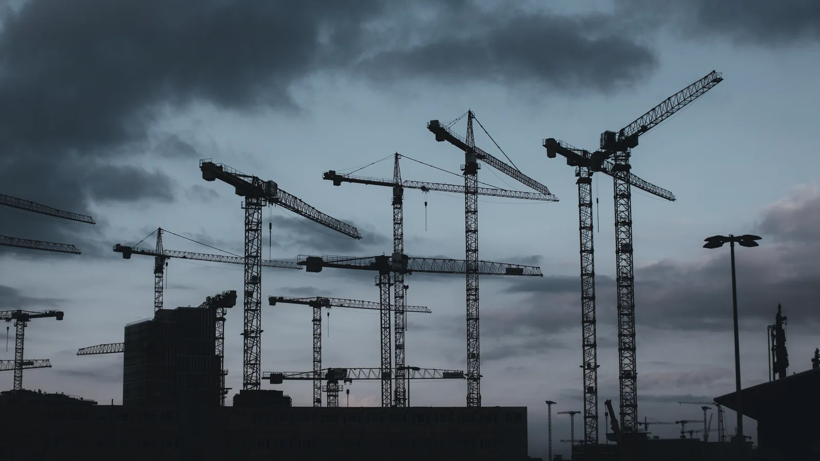 Forest of tower cranes silhouetted against a dusk sky