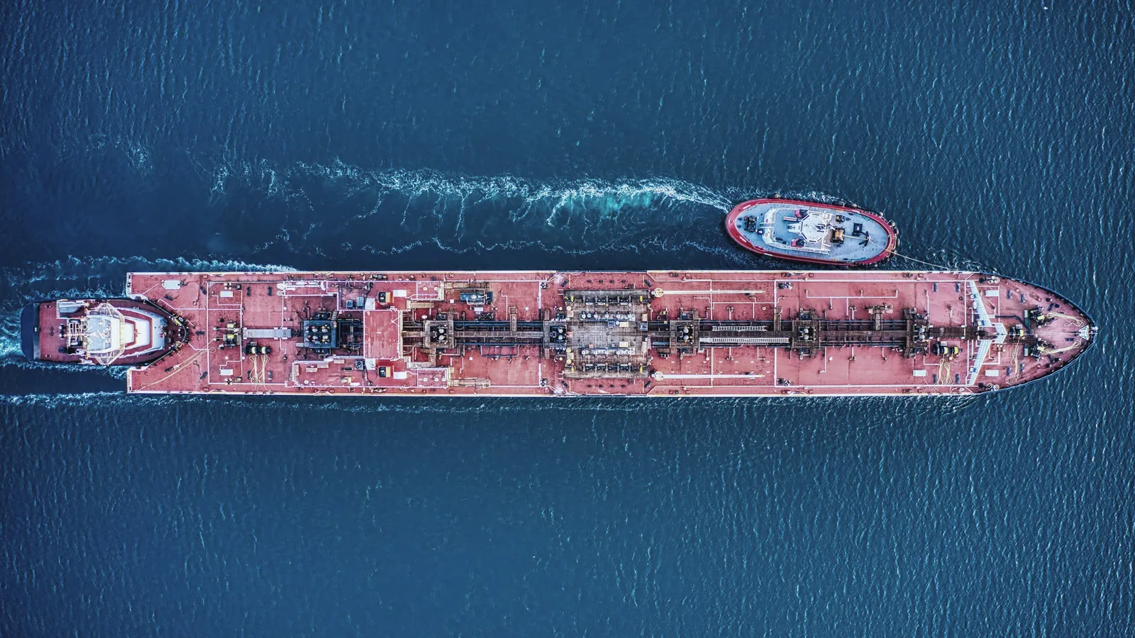 Top-down aerial of a tanker ship with a tug alongside